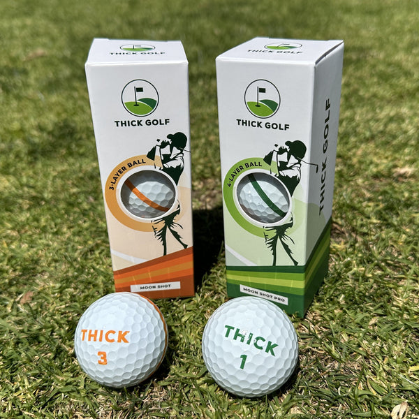 An orange-and-white Moon Shot sleeve and a green-and-white Moon Shot Pro sleeve standing on grass, with a ball with an orange THICK 3 logo and a ball with a green THICK 1 logo in front